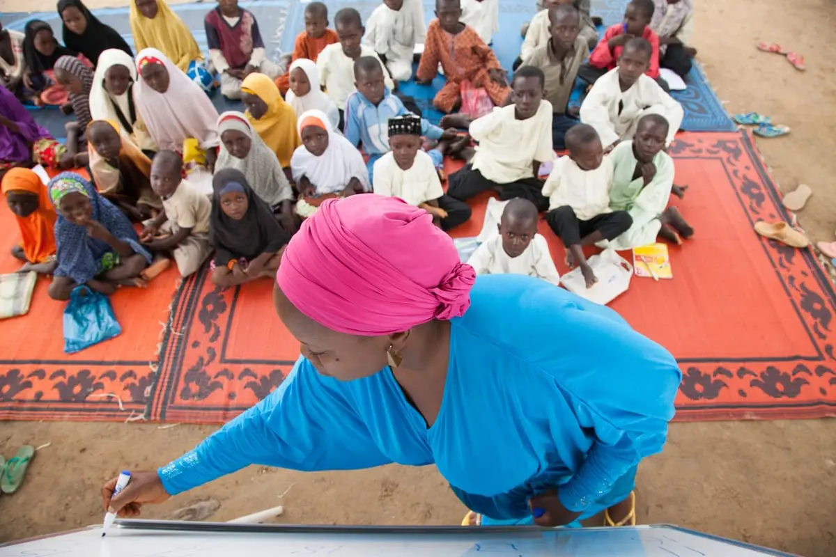 Apprentissage de la lecture et de l'écriture, Nigéria. Damisa Rahila, volontaire du projet SMILE financé par l'USAID, enseigne à des enfants à Sakwatawa, une petite communauté de l'État de Nasarawa, au Nigéria. Photo : Rawpixel.